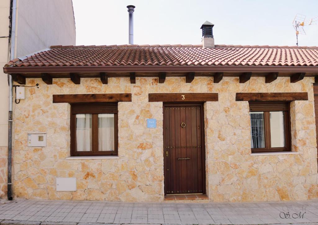 un edificio con una puerta marrón y dos ventanas en la casa del abuelo, en Sebúlcor