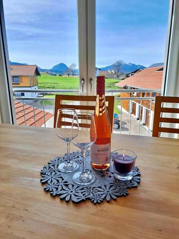 a bottle of wine and two glasses on a table at AllgäuBlick - Ferienwohnung mit Bergblick - Königscard in Hopferau