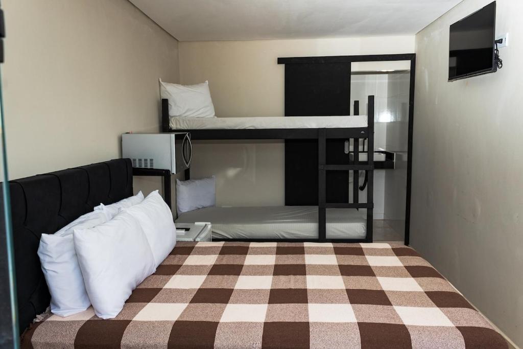 a bedroom with two bunk beds and a checkered floor at Pousada Caraguatatuba Praia Indaia Quarto 04 in Caraguatatuba
