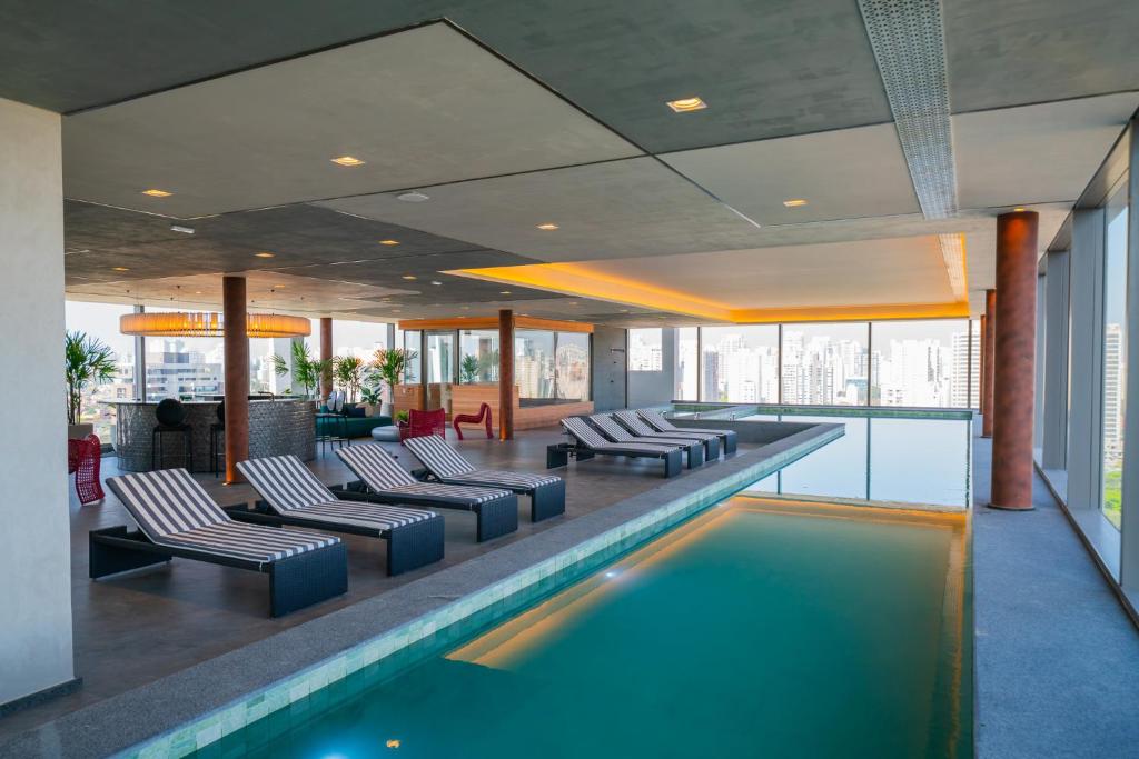 a swimming pool in a hotel with chairs and tables at Charlie For You Moema in Sao Paulo