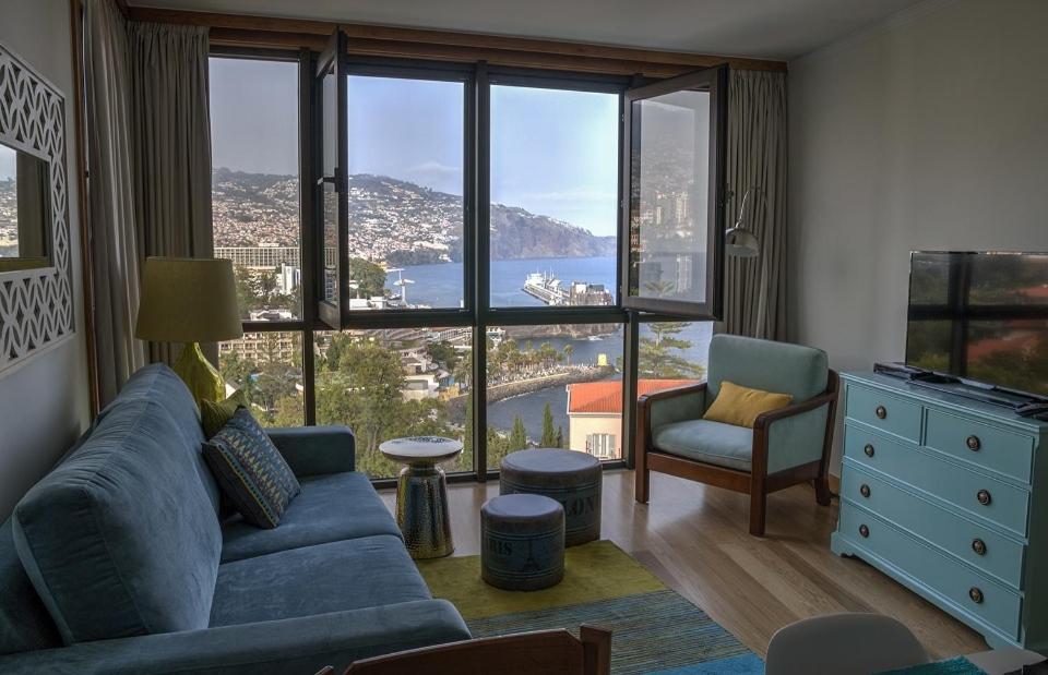 a living room with a blue couch and a large window at Monumental Apartment in Funchal