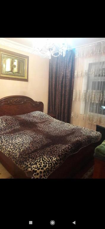 uma cama com estampa de leopardo num quarto com uma janela em Квартира em Samarkand