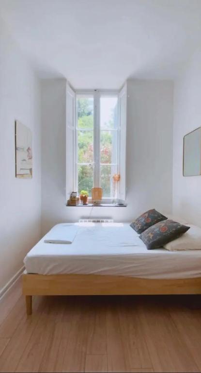 a bed in a white room with a window at Petite chambre sur cour aborée in Marseille