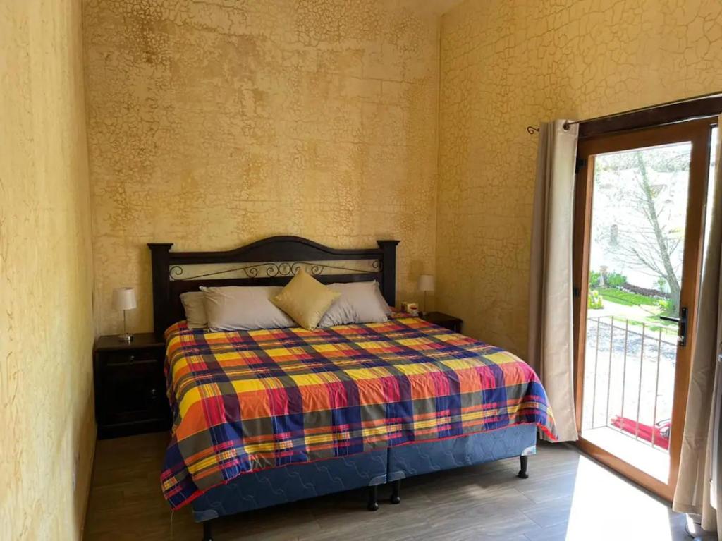 a bedroom with a bed with a colorful blanket at Casa Santuario in Antigua Guatemala