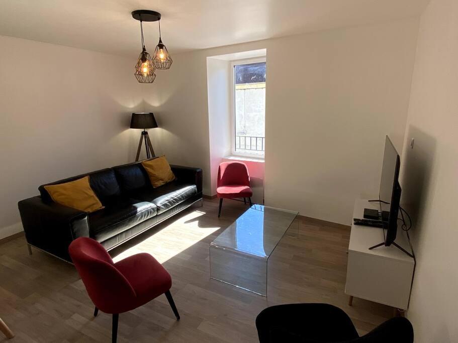 sala de estar con sofá negro y silla roja en Maison de ville des Bernardines, en Orgelet