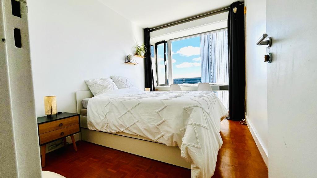una camera con un letto e una grande finestra di Montparnasse, 2 cozy private rooms in shared apartment a Parigi