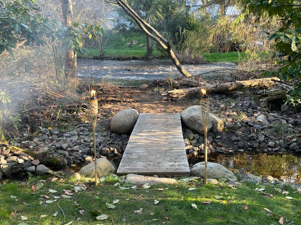 a wooden bridge over a stream with candles on it at Riverside Retreat in Gold Bar
