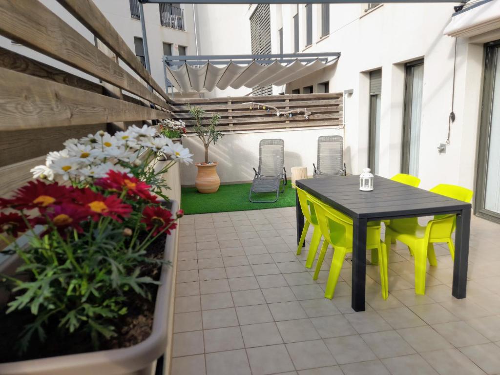 een patio met een tafel, stoelen en bloemen bij Apartamento Lliris Sol in L'Estartit