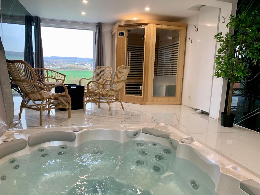uma banheira de hidromassagem numa sala de estar com cadeiras em Le Spanorama; gîte premium em Vincelles
