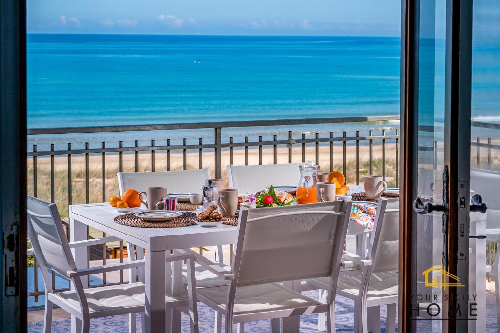 een tafel en stoelen met uitzicht op het strand bij Casa Vacanze Mare Dorato in Alcamo Marina