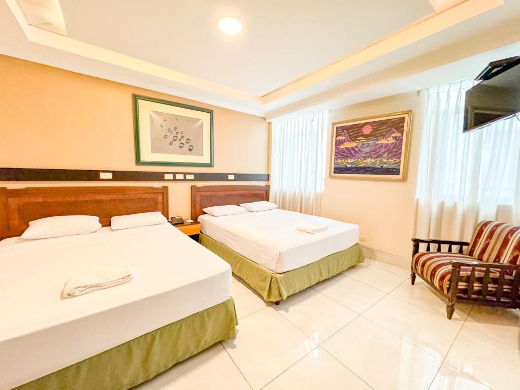 um quarto de hotel com duas camas e uma cadeira em GH Alexander Hotel em Guayaquil