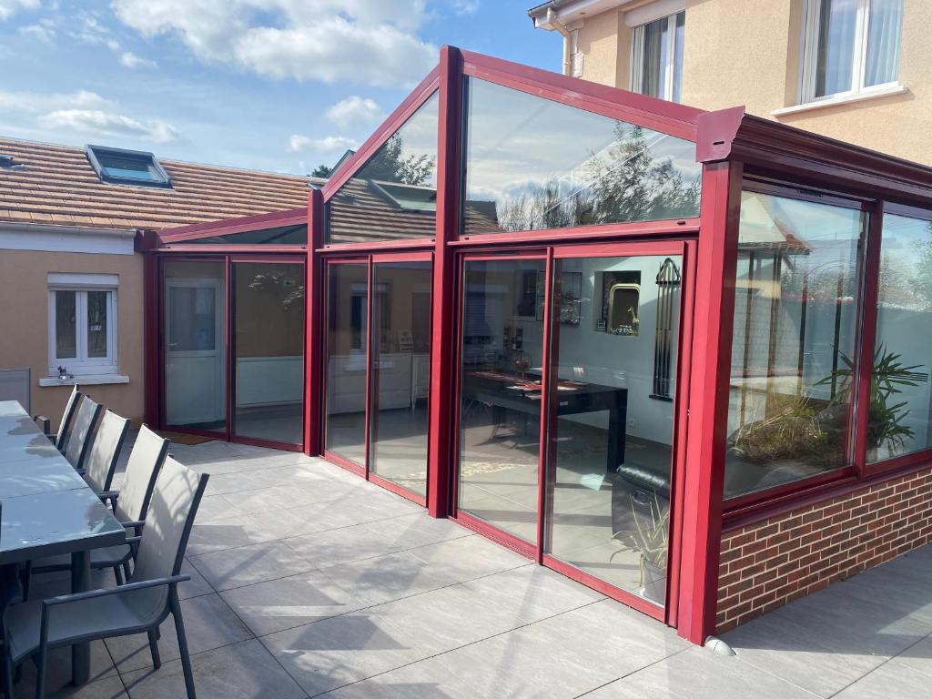 une véranda avec des portes en verre sur une terrasse dans l'établissement Dépendance avec Billard à proximité Zénith Rouen, à Le Grand-Quevilly