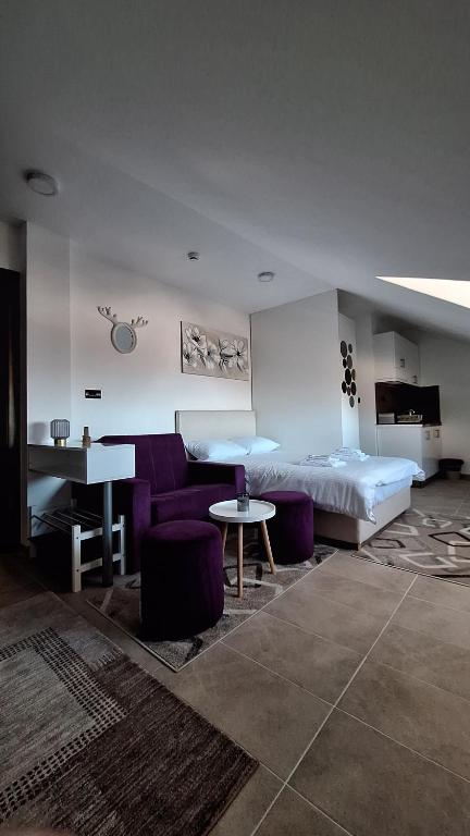a bedroom with a bed and a table and purple chairs at Apartman Marković - Milmari welnes & spa resort Kopaonik in Kopaonik