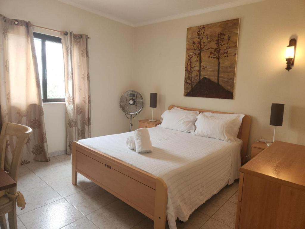 een slaapkamer met een bed met witte lakens en een ventilator bij Sunny House in Lagos