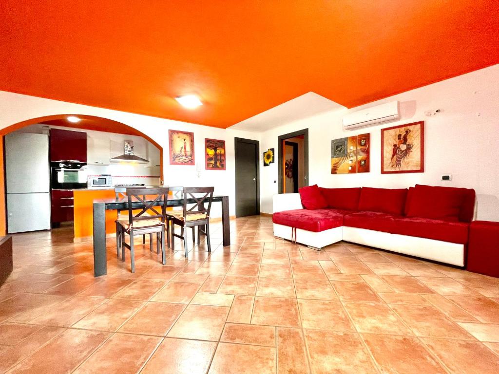 Una sala de estar con un sofá rojo y una mesa. en Orange House, en Bari Sardo