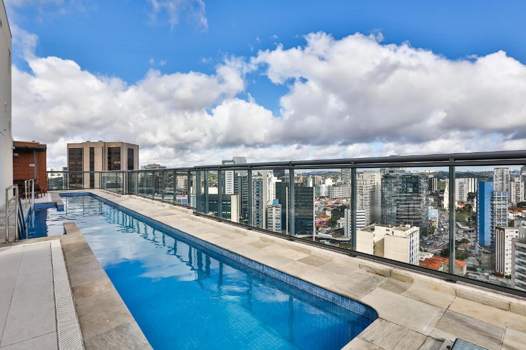a swimming pool on the roof of a building with a city skyline at Charlie Faria Lima in São Paulo