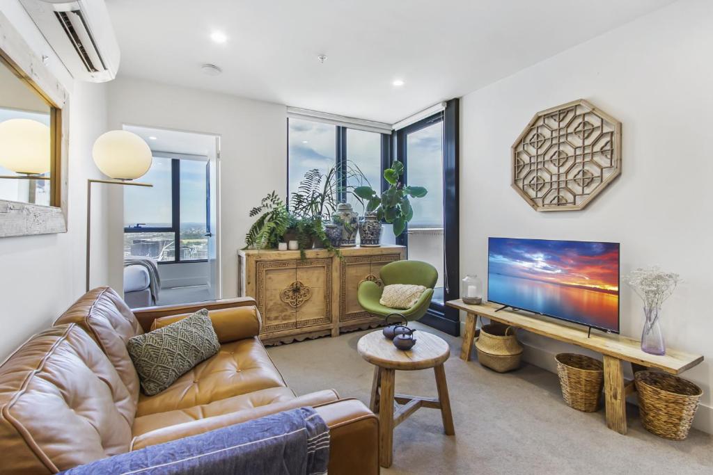 a living room with a couch and a tv at Atop the Melbourne CBD with Panoramic Views in Melbourne