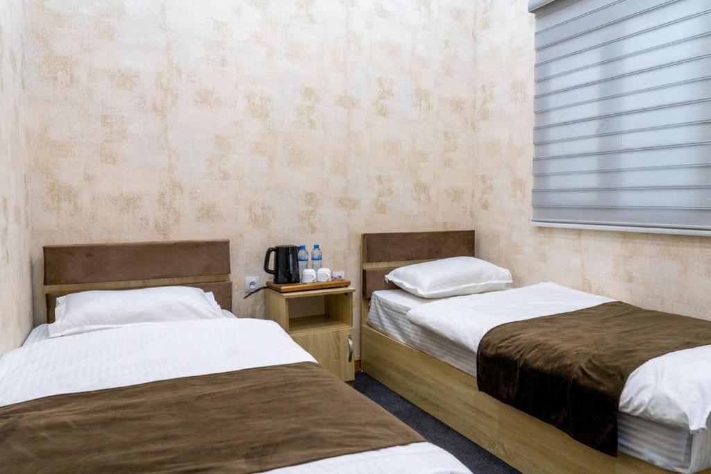 twee bedden naast elkaar in een kamer bij Muntazir Hostel in Yakkasaray
