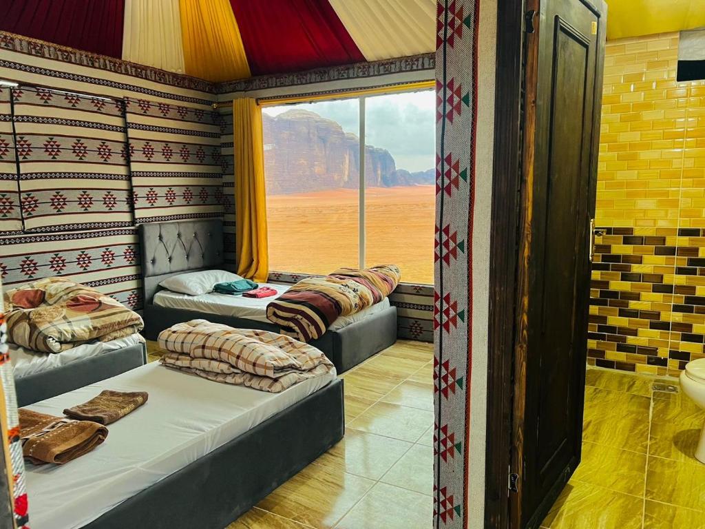 desert splendor camp & jeep tours في وادي رم: غرفة بثلاث اسرة ونافذة