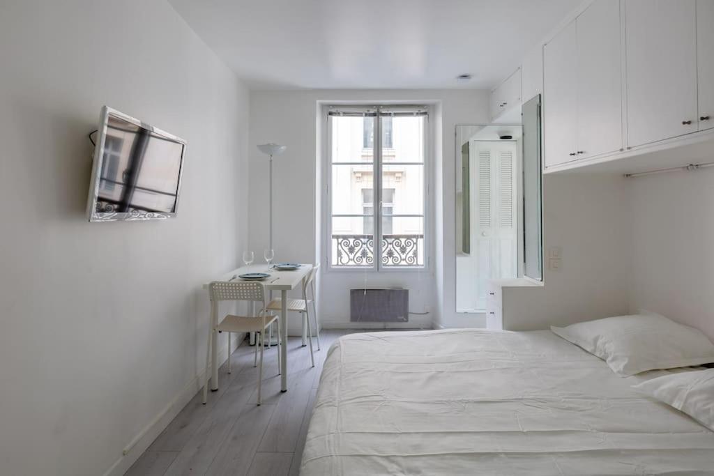 une chambre blanche avec un lit et un bureau dans l'établissement Le LONGCHAMP Paris 16 ème, New and perfectly located apartment, à Paris
