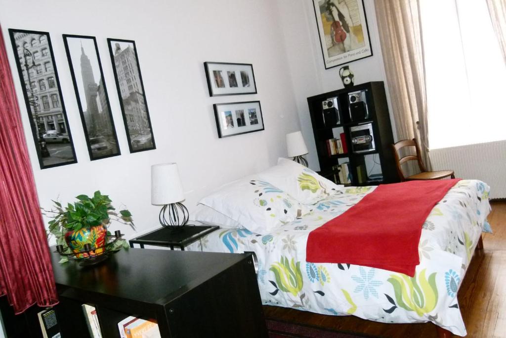 Charmant appartement 3 pers Perrache Confluence في ليون: غرفة نوم بسرير وطاولة مع بطانية حمراء