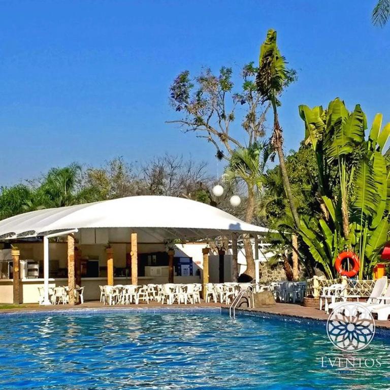 a pool at a resort with chairs and a pavilion at Hotel Coral Cuernavaca in Temixco