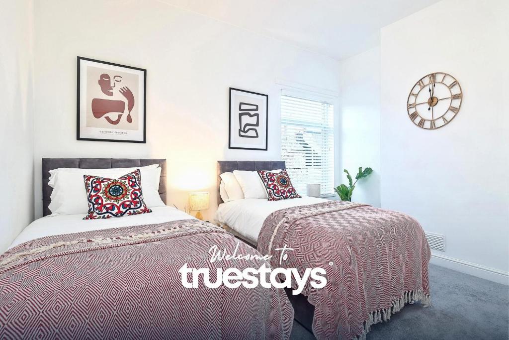 ein Schlafzimmer mit 2 Betten und einer Uhr an der Wand in der Unterkunft Fielding House by Truestays - NEW 3 Bedroom House in Stoke-on-Trent in Stoke on Trent