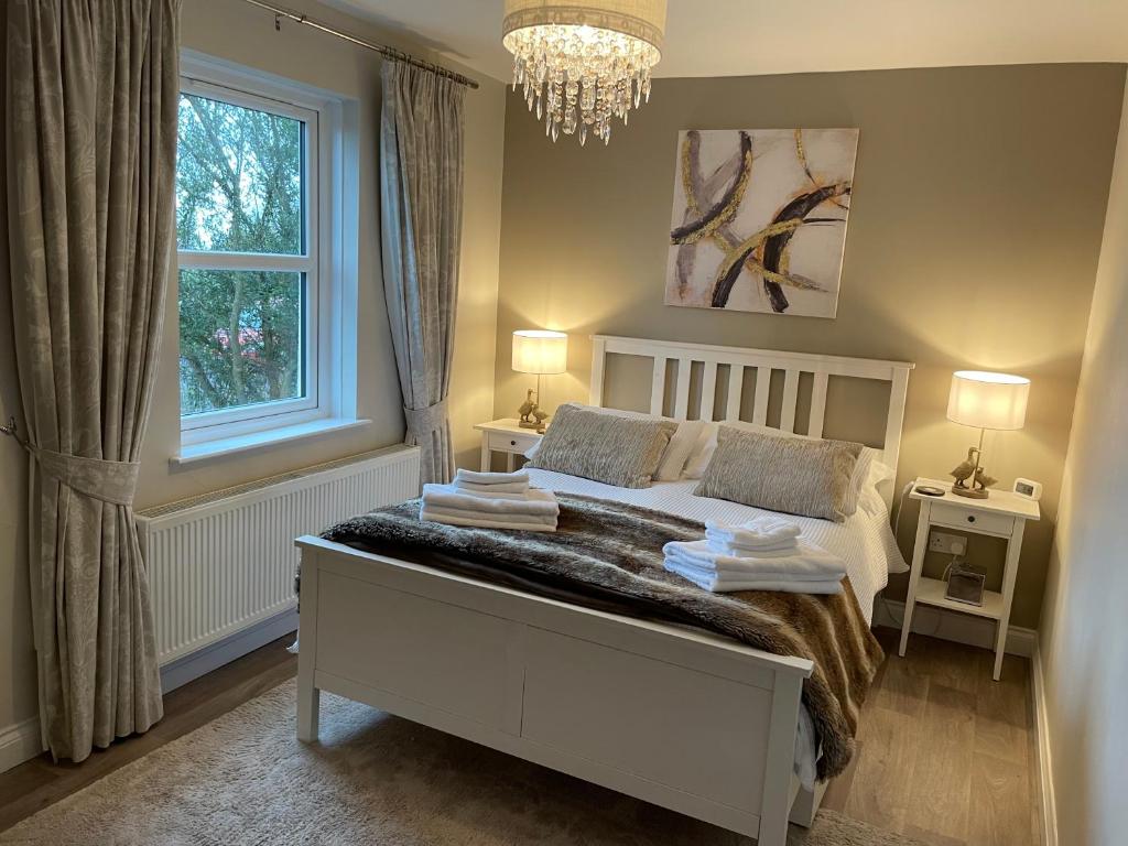 1 dormitorio con 1 cama blanca con 2 lámparas y una ventana en Loughview Lodge en Whitehead