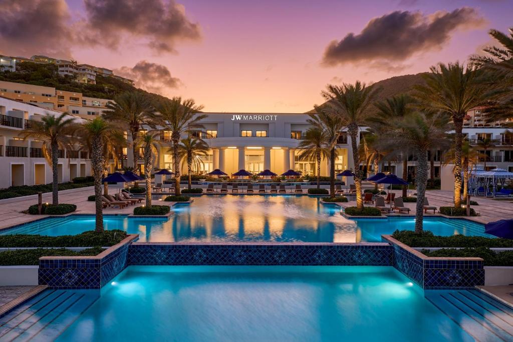 - une piscine bordée de palmiers et un bâtiment dans l'établissement JW Marriott St Maarten Beach Resort & Spa, à Dawn Beach