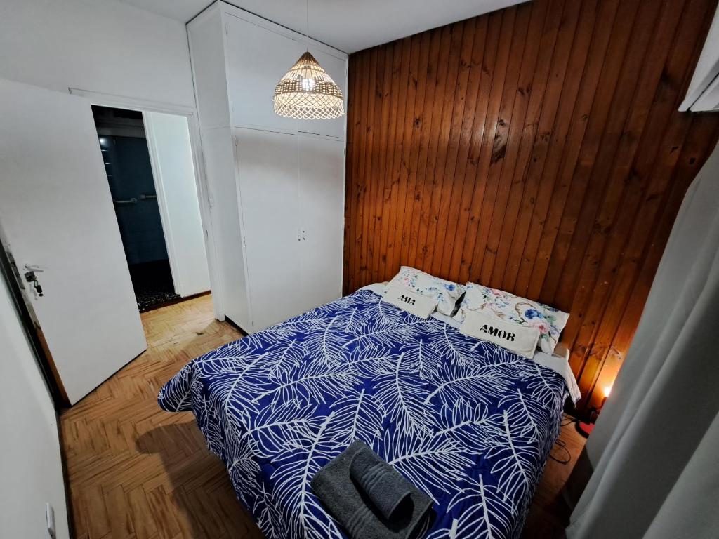 a bedroom with a bed with a blue and white comforter at Belgrano Home - Casa con jardín cerca del Aeropuerto de Ezeiza, hasta 7 pax in Monte Grande