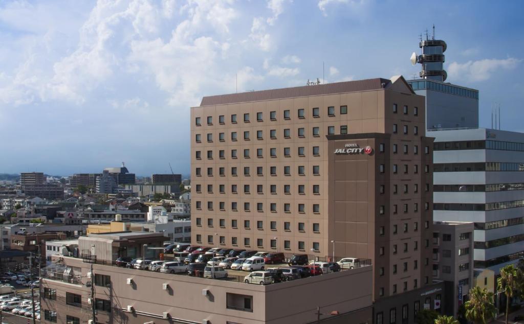 um edifício alto com carros estacionados numa cidade em Hotel JAL City Miyazaki em Miyazaki