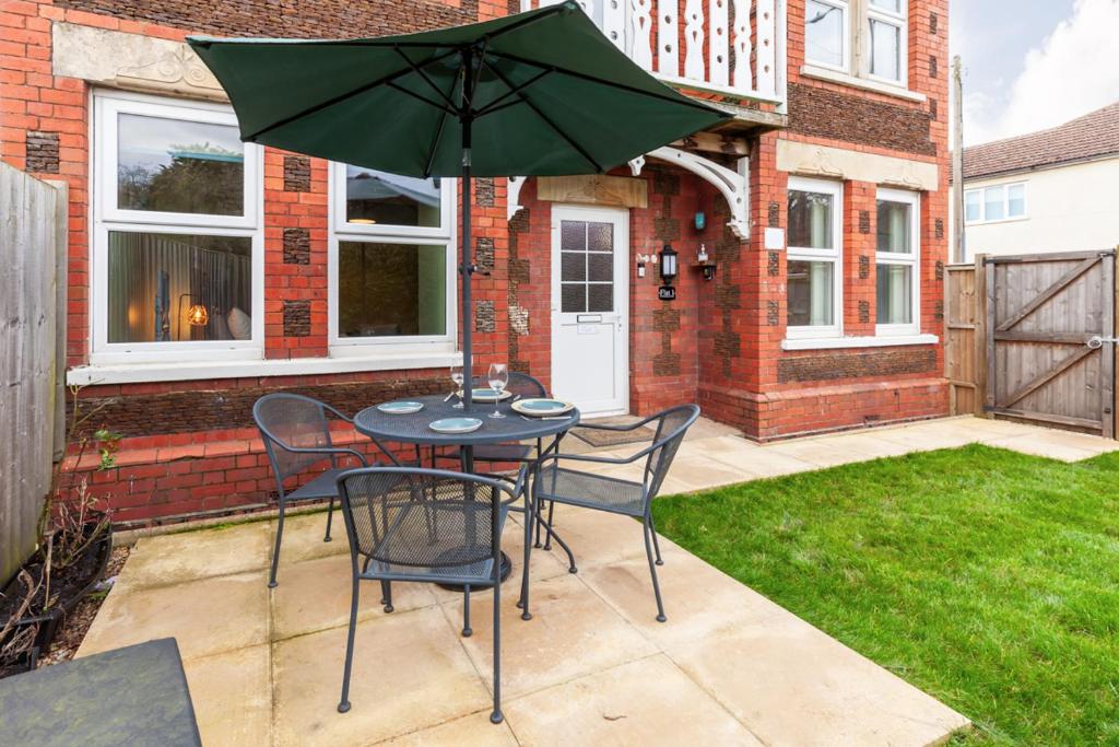 a patio with a table and chairs and an umbrella at Rambler’s Retreat in Dersingham
