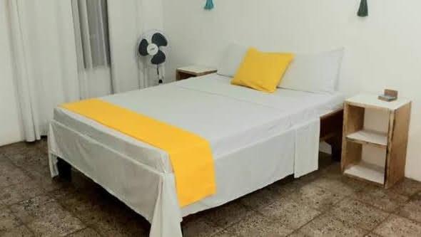Una cama blanca con una almohada amarilla encima. en rooms megi terminal, en Cahuita