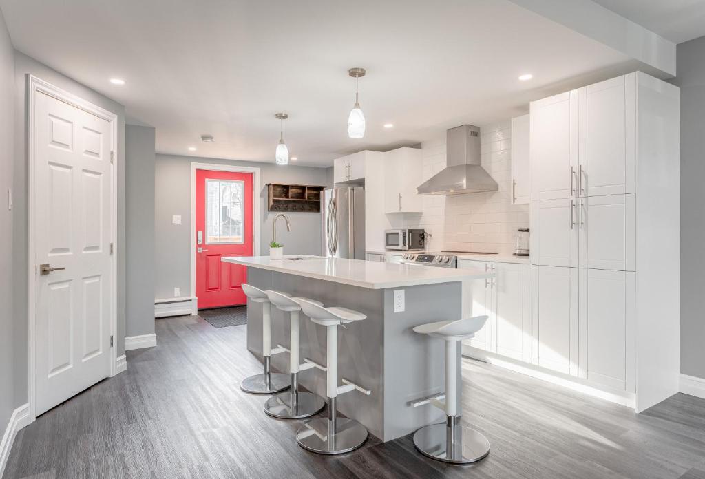 una cocina con armarios blancos y una isla con taburetes. en Modern Downtown 3BR 2B Home, en Yellowknife