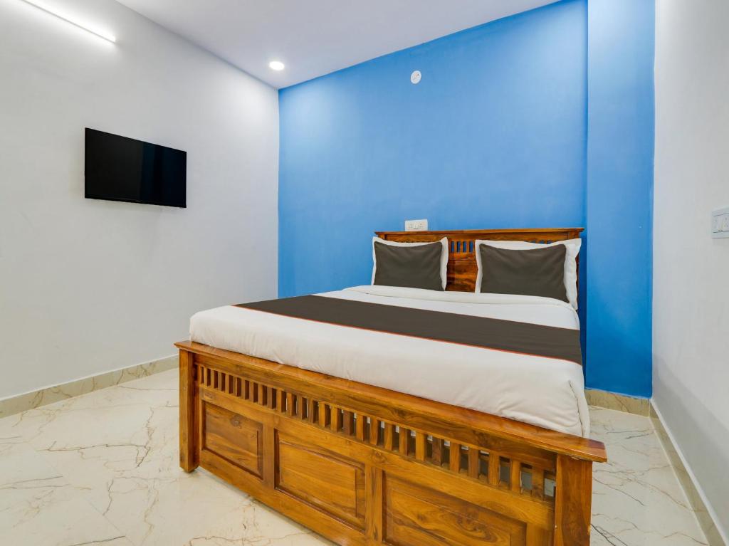 a bedroom with a bed with a blue wall and a tv at Collection O Hotel SR Grand in Bībīnagar