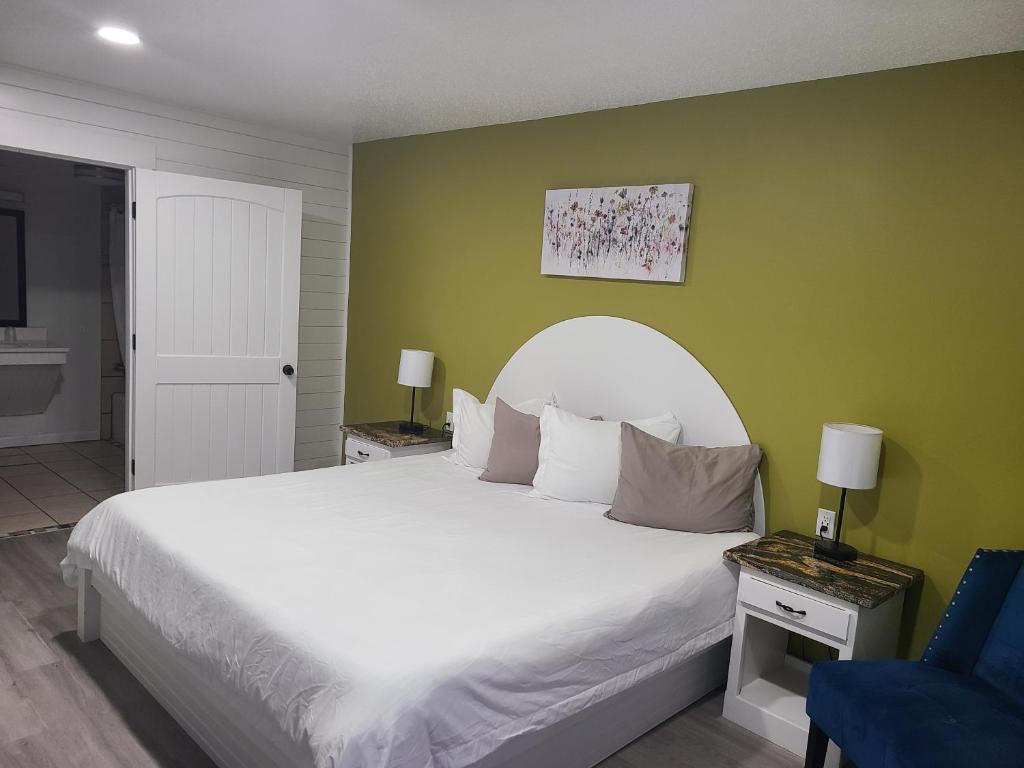 1 dormitorio con cama blanca y pared verde en Blue Sky Inn- Veteran Owned, New Breakfast Area, Rennovated Rooms, 5 plus acres for you and your pet to roam, NEW Fire Pit, en Blue Ridge