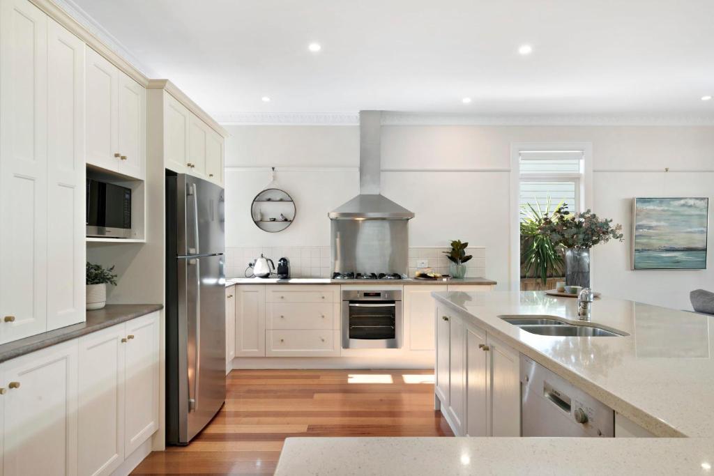 a kitchen with white cabinets and stainless steel appliances at Essendon Allambee Haven 4BR in Melbourne