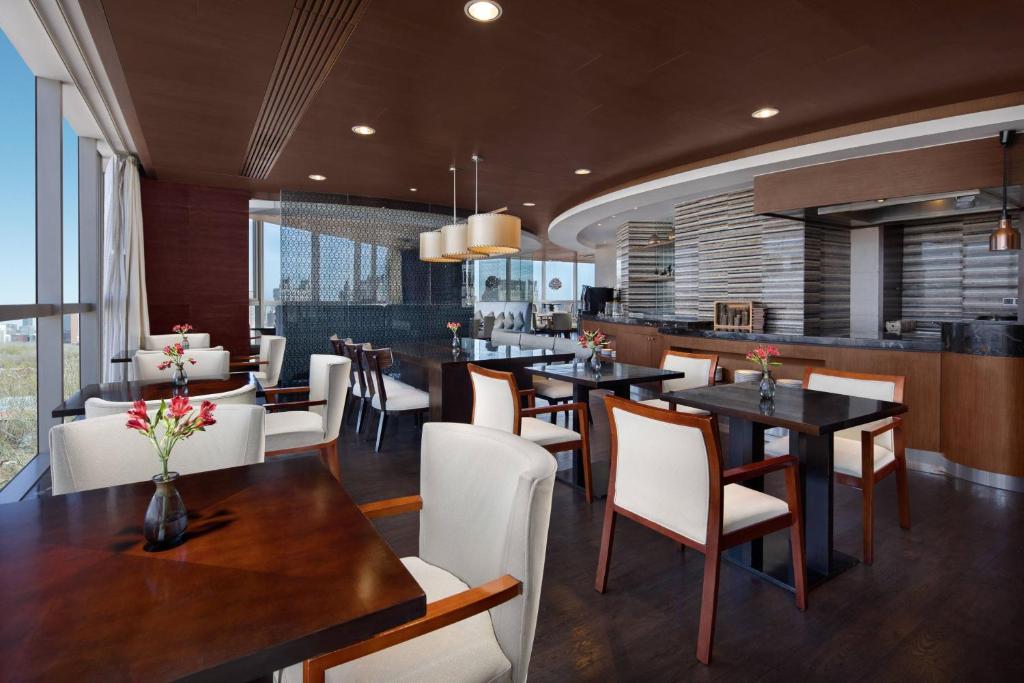 a dining room with tables and white chairs at Beijing Marriott Hotel Northeast in Beijing