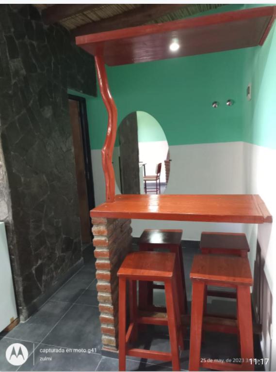 een houten tafel en twee krukken in een kamer bij Flor de los andes in Fiambala