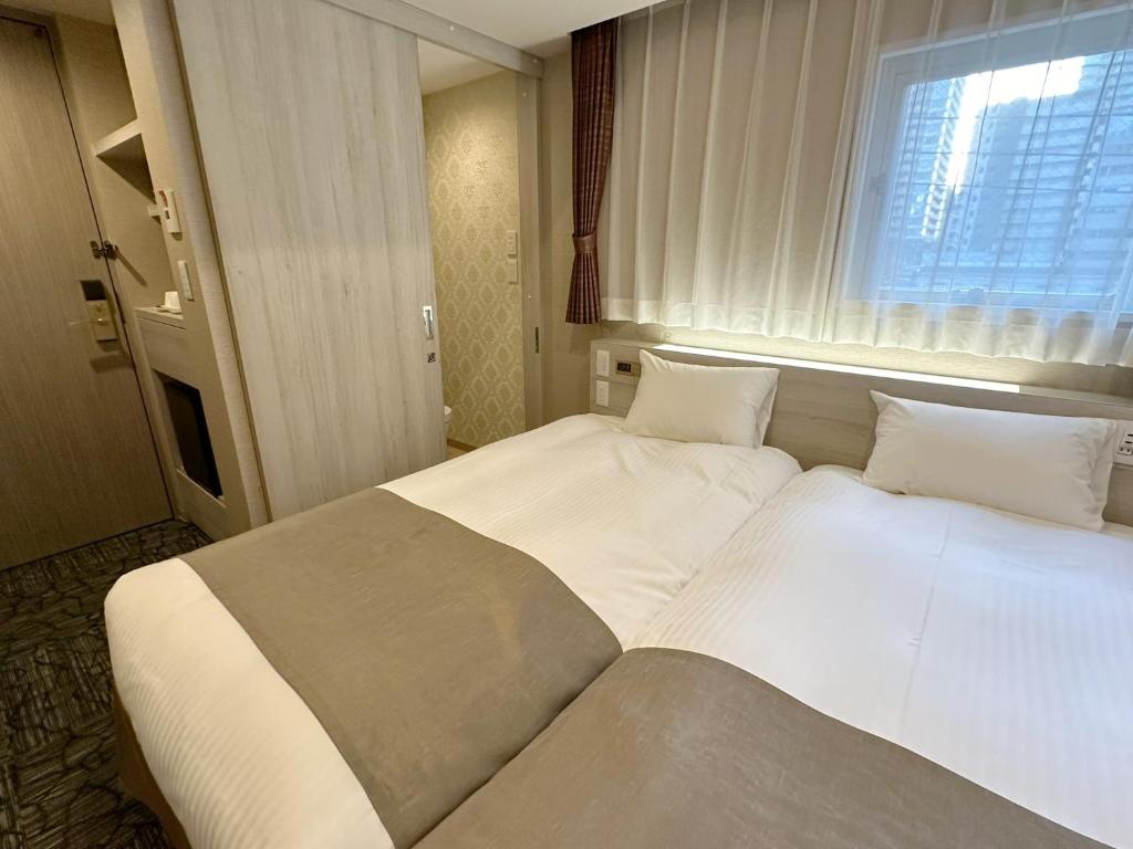 a large white bed in a room with a window at S.Training Center Hotel Osaka in Osaka