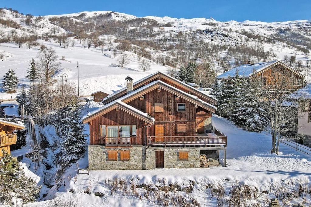 uma cabana de madeira na neve com uma montanha em grand chalet LB-3-1 em Saint-Marcel