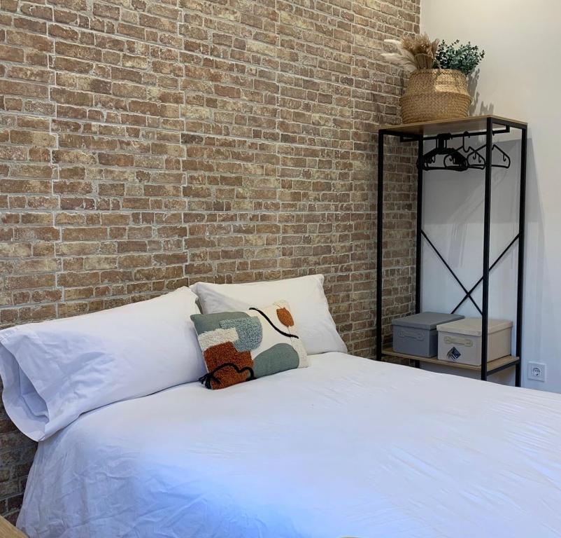 a bed in front of a brick wall at Valencia beach rooms in Valencia