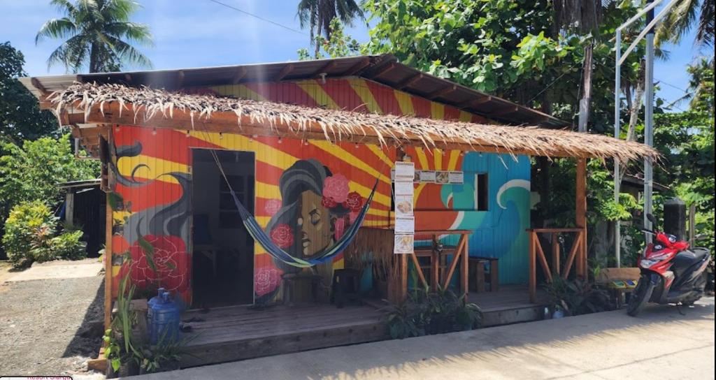 una casa colorida con una moto estacionada frente a ella en Alegreya Homestay + Cafe, en General Luna