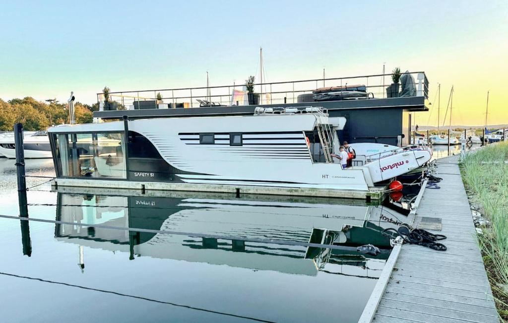 a boat docked at a dock with its reflection in the water at Hausboot Hafensuite De Luxe in Sagard
