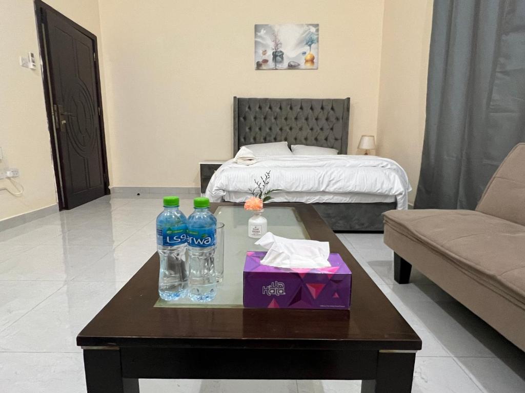 ein Wohnzimmer mit einem Tisch und Wasserflaschen darauf in der Unterkunft Cozy Private Studio Apartment Near Airport in Abu Dhabi
