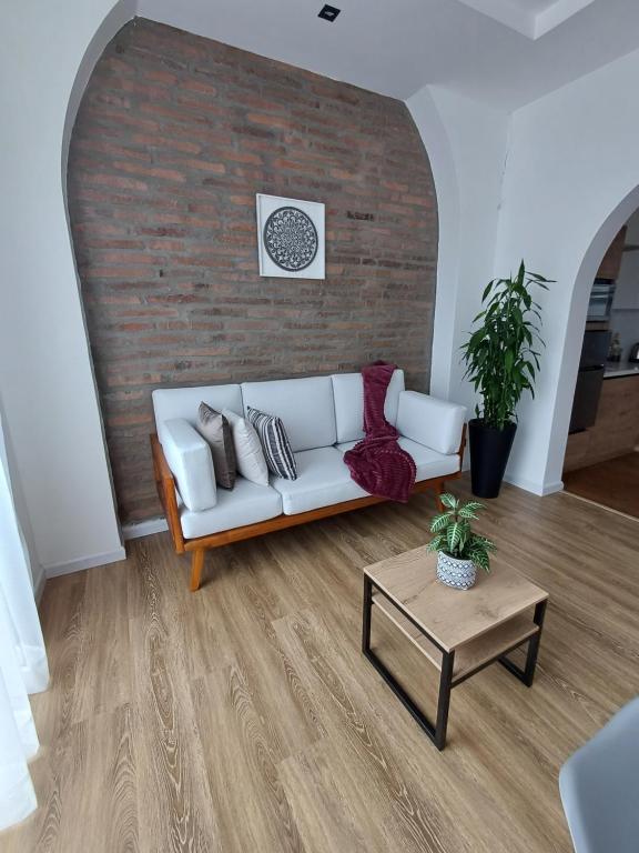 ein Wohnzimmer mit einem weißen Sofa und einer Ziegelwand in der Unterkunft Suite en el centro de la ciudad de Cuenca in Cuenca