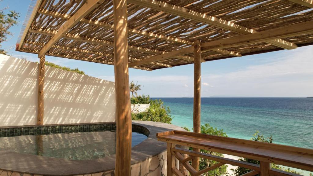 a wooden pergola with the ocean in the background at Akasha Beach Club in Bulukumba