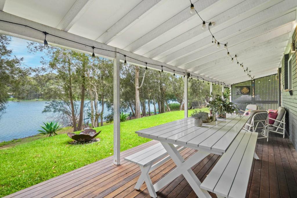 a picnic table on a deck with a view of the water at Scenic 4-Bed Lake House 5-min Walk to Avoca Beach in Avoca Beach