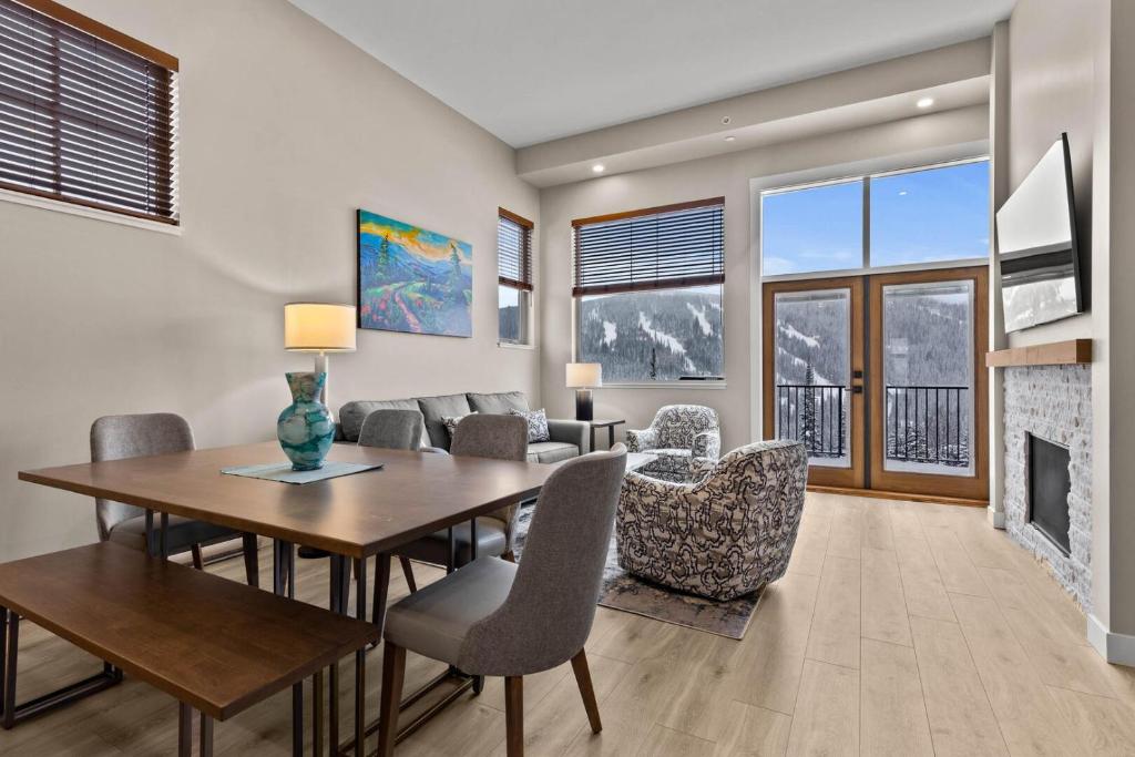 a dining room with a table and chairs and a fireplace at Powder Heights #21 townhouse in Sun Peaks