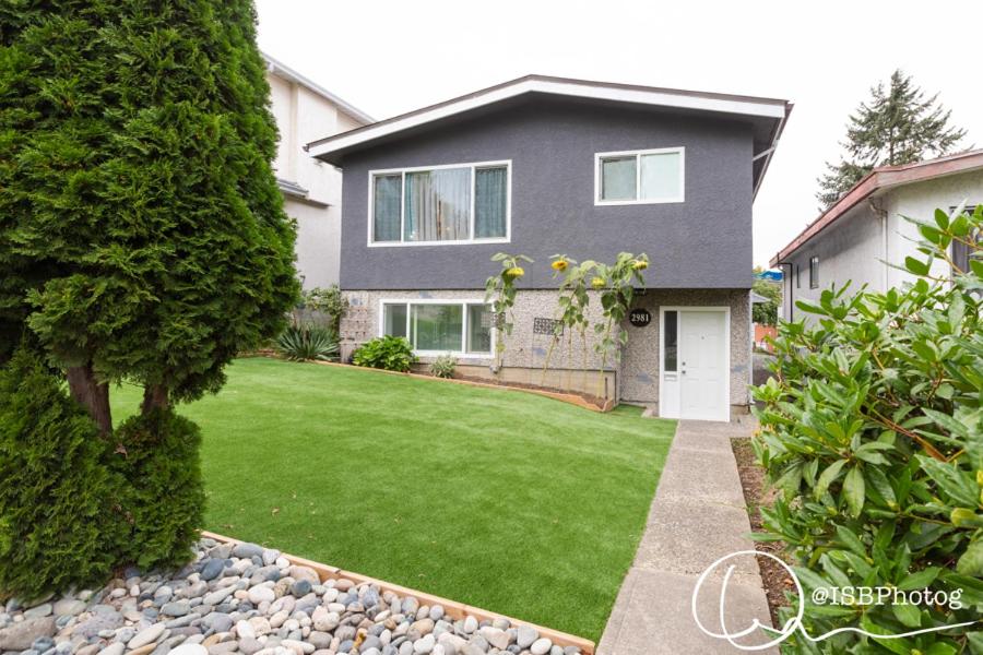 une maison avec une pelouse verte devant elle dans l'établissement Suite Sunrise, à Vancouver